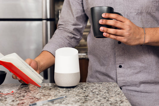 person using smart speaker in kitchen drinking coffee and reading